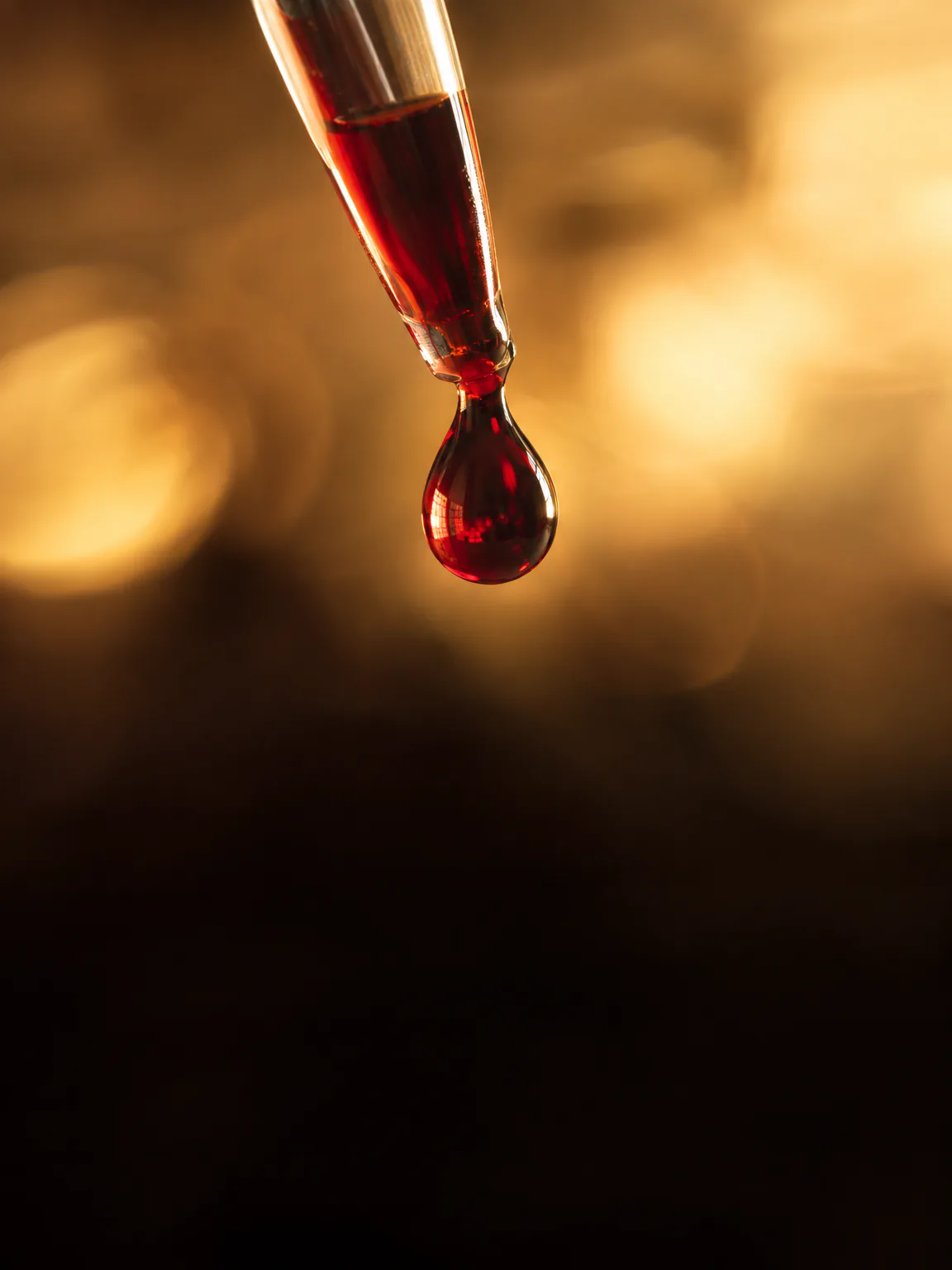 Illustration: a single drop of blood hanging from a glass pipette